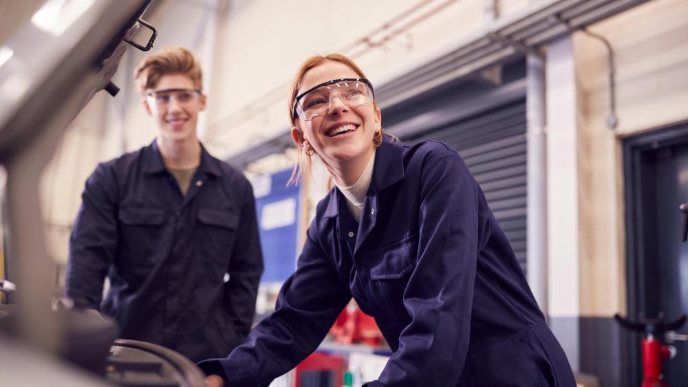 Two mechanics lean over car engine
