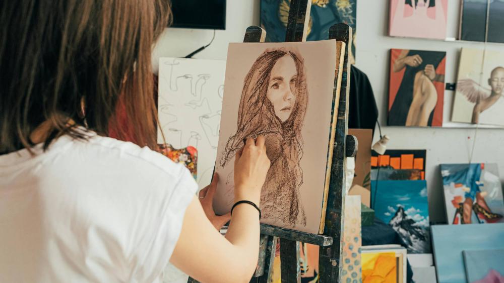 Someone drawing a person using an easel