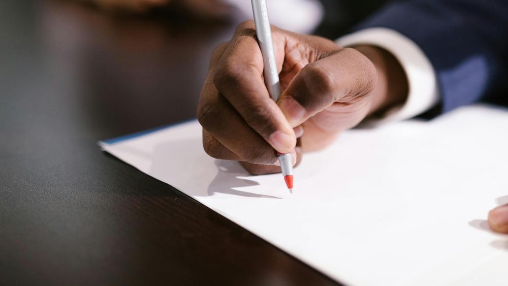 Close up of hand with pen about to write on blank paper
