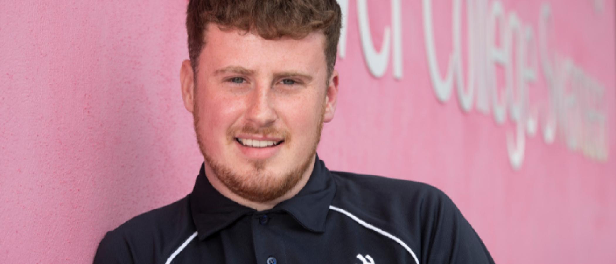 Ben yn ei grys WorldSkills UK, yn sefyll tu allan i Gampws Tycoch